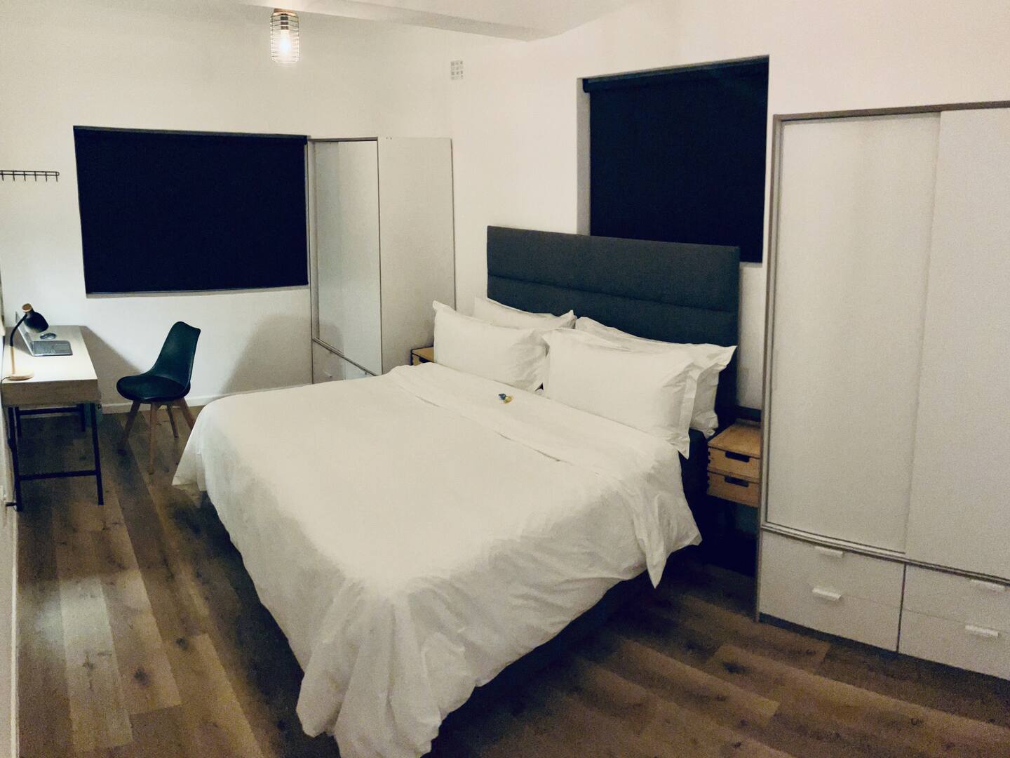 Bedroom with a king bed, white linen, work desk and built-in wardrobes