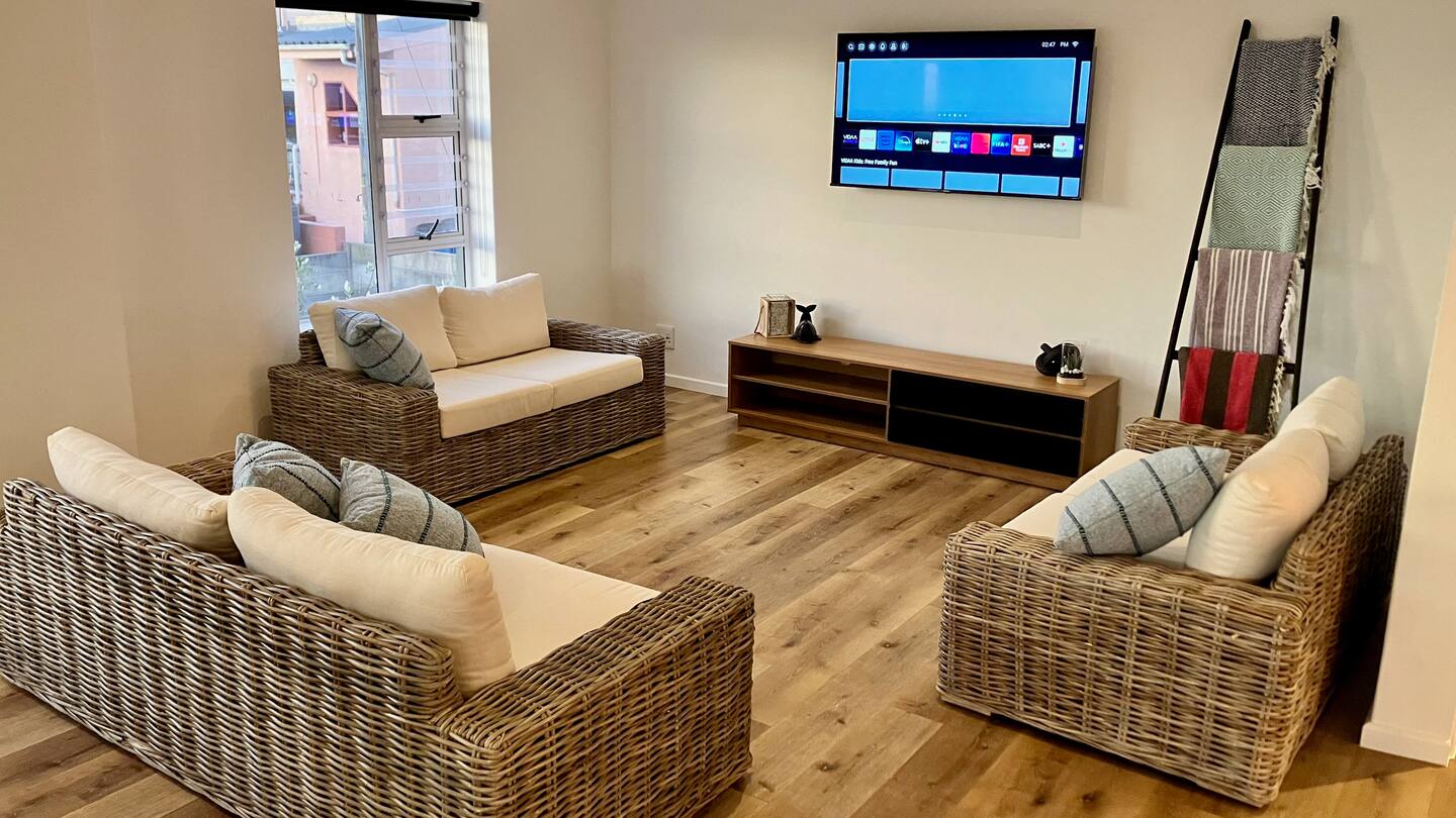 Living room with woven sofas, wall-mounted TV and sunlit windows